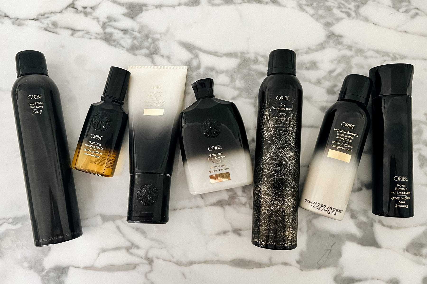 Oribe haircare products arranged on a marble surface.